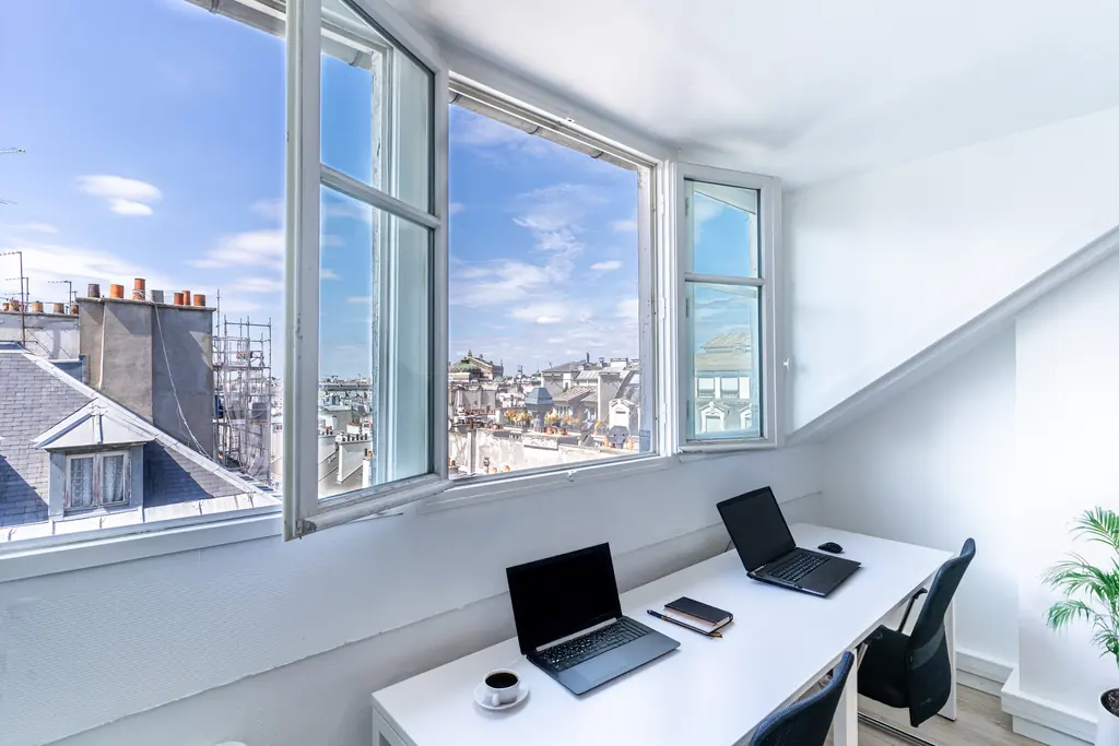 Bureau du 8e étage, postes face aux fenêtres et vue sur les toits de Paris